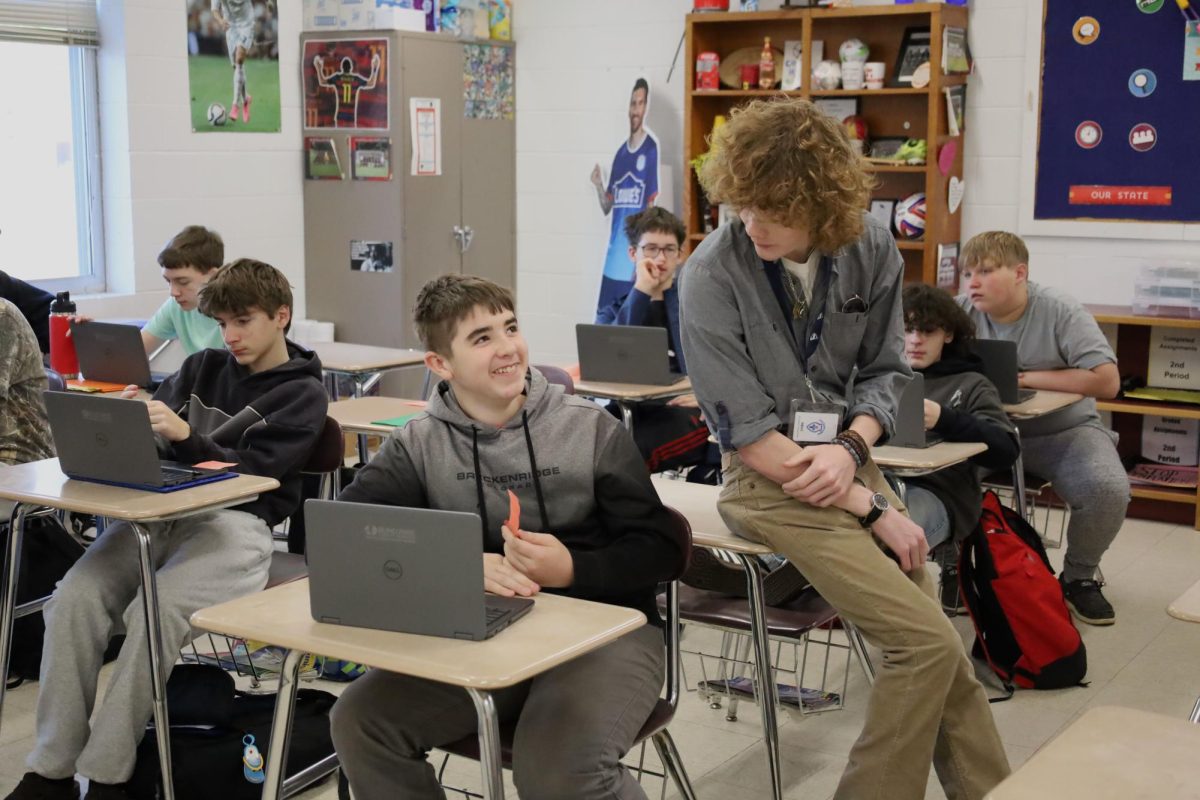 Jack Sandifer (12) leans in, talking with a 7th grade student about the impacts of the industrial revolution.